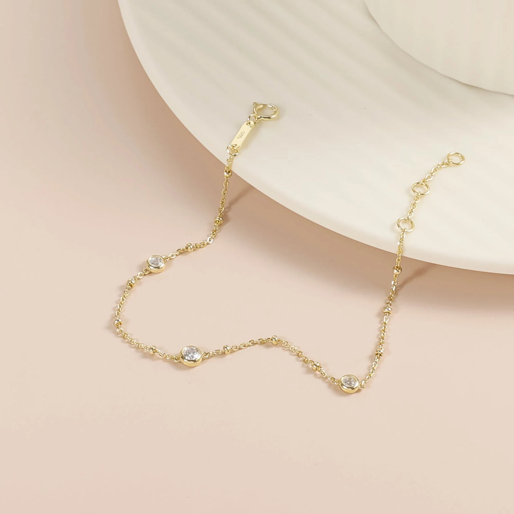 Close view of Nyla gold bubble bracelet draped beside a ceramic dish