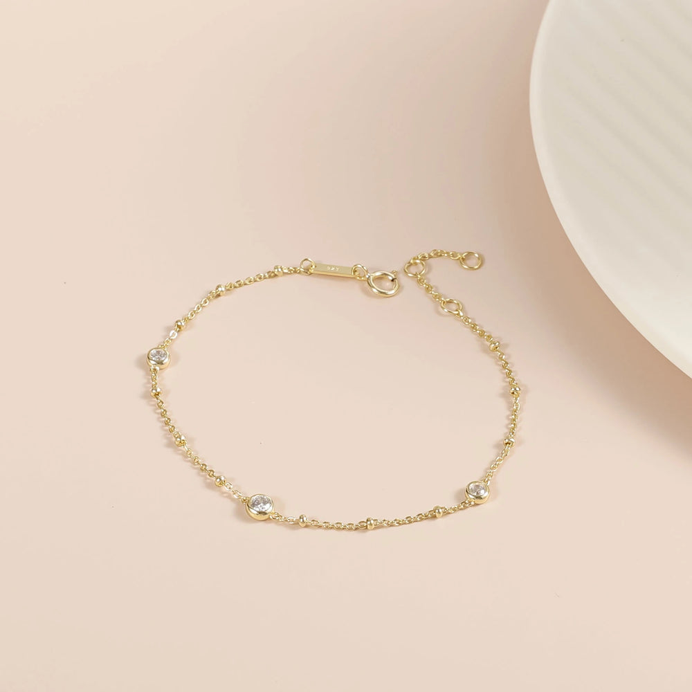 Nyla gold moissanite bubble bracelet laid flat, showing its delicate chain and three stone stations