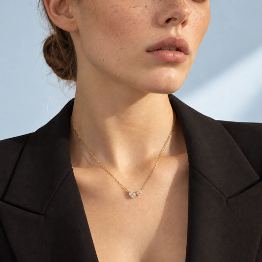 Close-up of the Lucía double pear moissanite necklace in gold worn by Mara