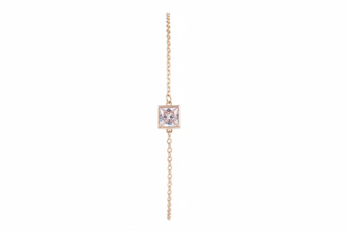 A delicate yellow gold chain bracelet featuring a square bezel-set clear gemstone pendant.