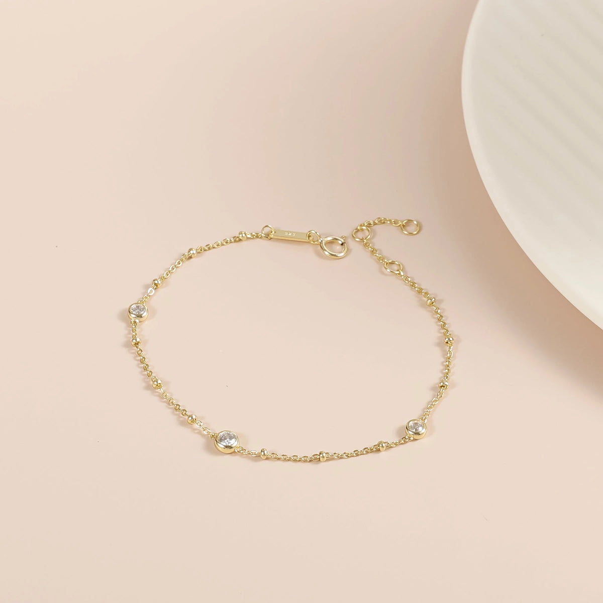 Nyla gold moissanite bubble bracelet laid flat, showing its delicate chain and three stone stations