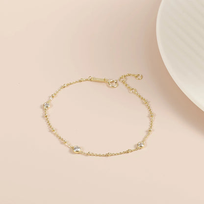 Nyla gold moissanite bubble bracelet laid flat, showing its delicate chain and three stone stations